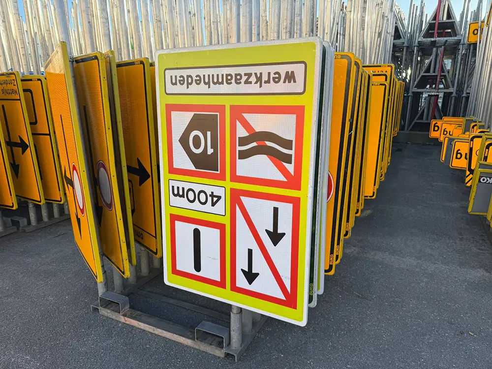 Temporary road traffic signs stored on racks, used for managing roadworks and directing vehicles safely