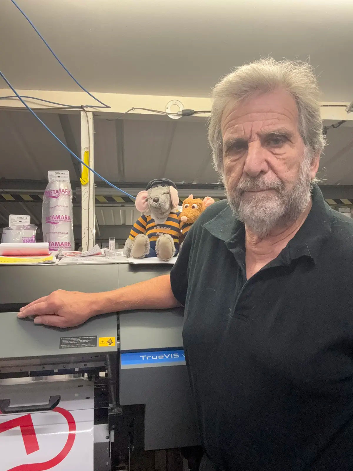 Curtis Signs team member standing beside a Roland DG TrueVIS printer in the production workshop