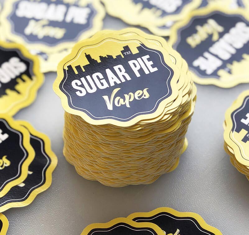 Une pile d'étiquettes pour produit entourée d'autres stickers en vinyle imprimés et découpés