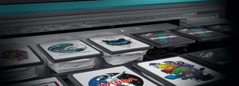 Several T-shirts with different designs in a Direct-to-Garment printer