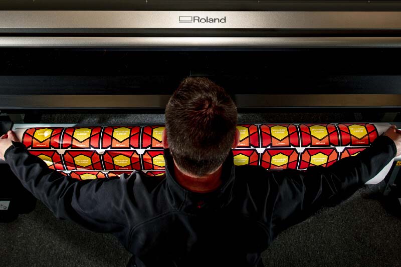 Alex Ligget retirando etiquetas de botellas de su impresora / cortadora UV 