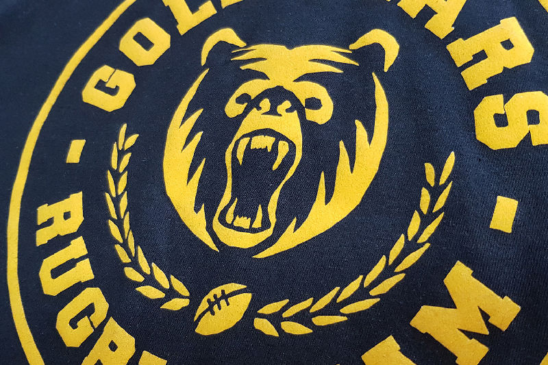 A yellow HTV logo on a dark fabric
