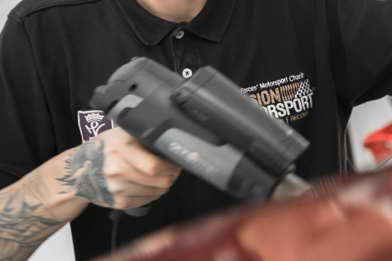 Utilizzo di una pistola a caldo per ammorbidire il vinile prima dell'applicazione sul veicolo (fonte: Mission Motorsport)