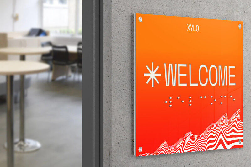 Ein bedrucktes orangefarbenes Schild mit Braille-Schrift