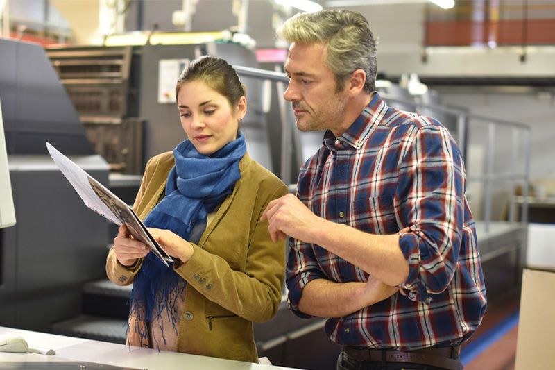 A print business owner reviewing print with a client