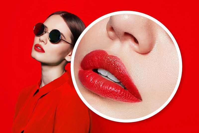 Frau mit roten Lippen und dunkler Brille, die ganz in Rot gekleidet ist, steht vor einer roten Wand. Das Bild enthält außerdem einen weißen Kreis, der auf die roten Lippen der Frau zoomt, um die rote Farbe und die Struktur der Lippen zu betonen.